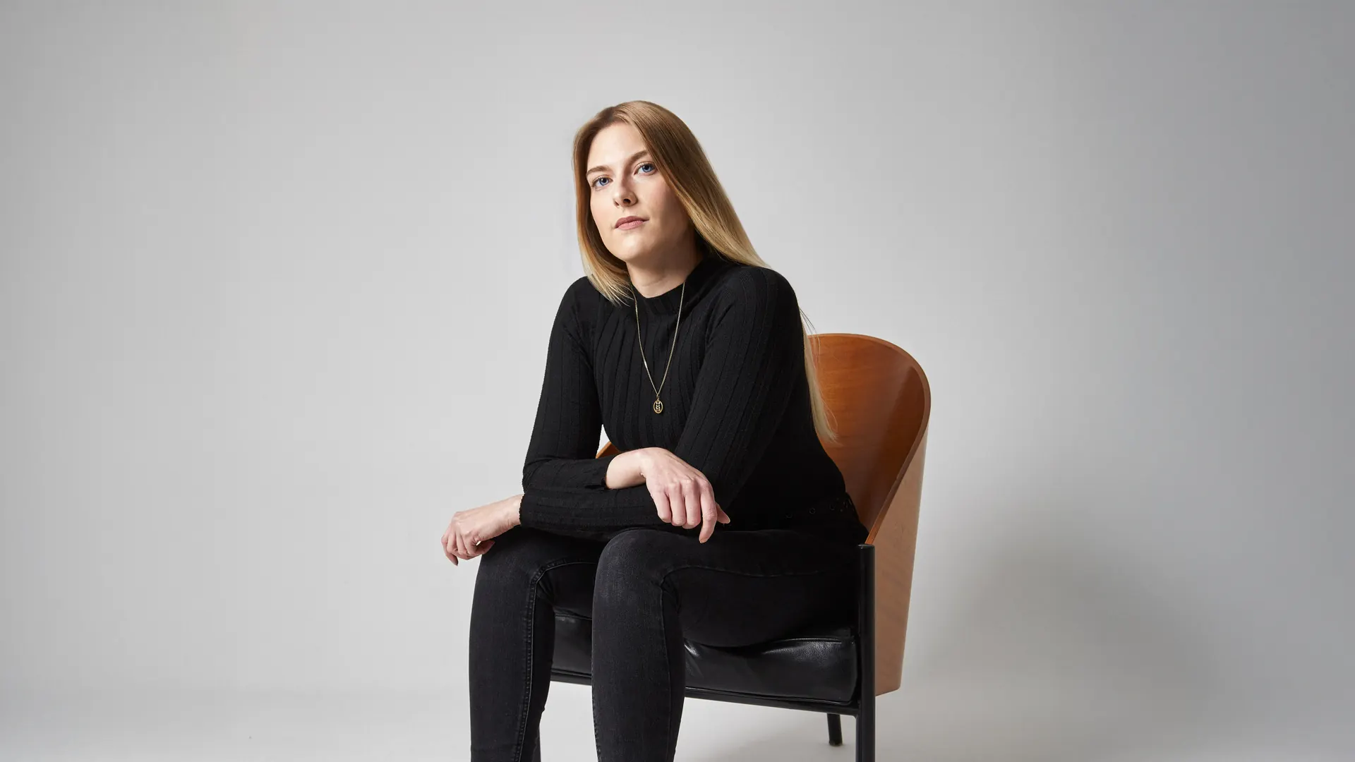 Michelle Leopold, Kommunikationsdesignerin, sitzt auf einem Holzstuhl